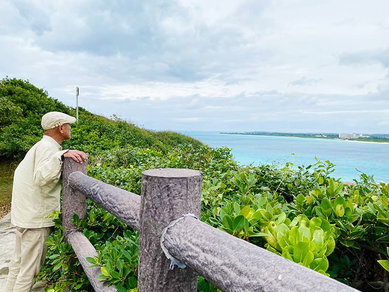 高台から沖縄の海を眺めている宮平会長の写真